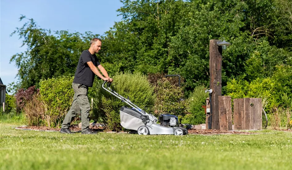 Gartenarbeit - Mann mäht Rasen